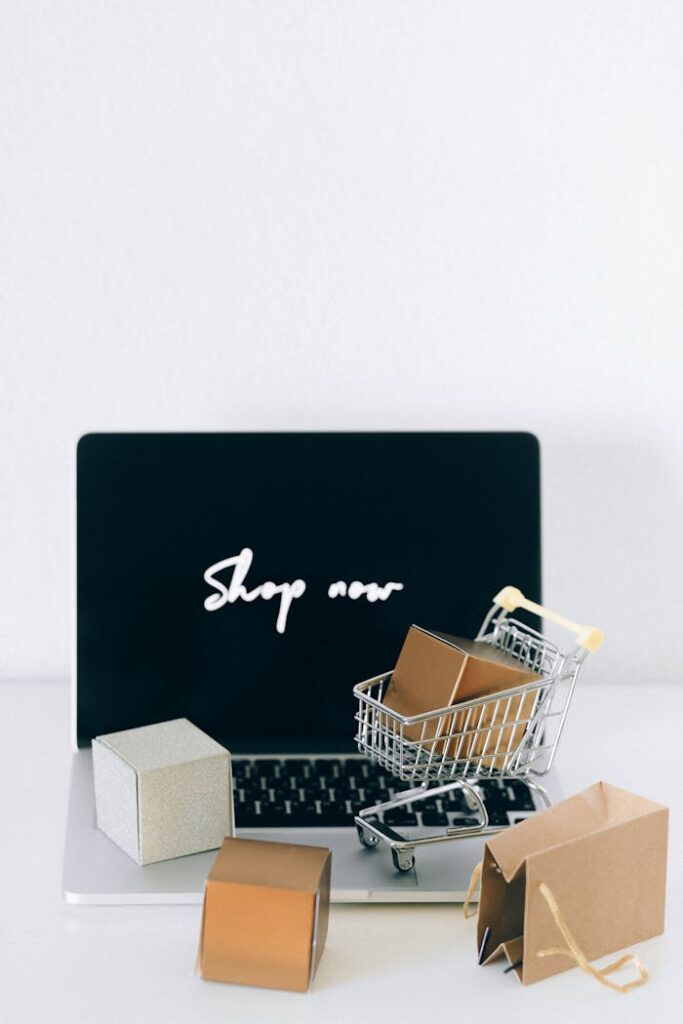 pexels-photo-6214471 Minimalist online shopping setup with laptop, cart, and packages symbolizing e-commerce.